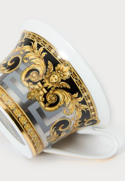 Πορσελάνινη κούπα καφέ με κωνικό σχήμα, που διαθέτει περίτεχνα χρυσά και μαύρα μπαρόκ σχέδια, ομαλή λευκή επιφάνεια και καμπυλωτή λαβή.