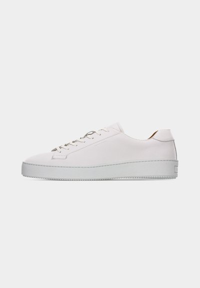 Weißer Sneaker aus Leder im Low-Top-Stil mit weißen Schnürsenkeln, flacher strukturierter Gummisohle und minimaler Naht, von der Außenseite auf weißem Hintergrund gezeigt.