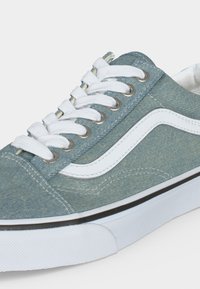 Χαμηλό sneaker με ύφασμα ελαφρώς γαλάζιο τζιν, λευκά κορδόνια, λευκή πλαϊνή ρίγα και χοντρή λευκή λαστιχένια σόλα με μαύρο περίγραμμα.