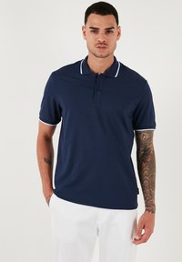 Mornarica polc shirt iz gladkega materiala, z odprtjem z elementi na tri gumbe, belimi kontrastnimi akcenti na ovratniku in manšetah, v sproščenem kroju.