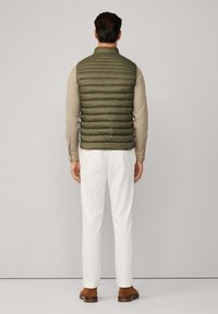 Vihreä puhviviitta vaakasuoralla tilkkutööhkällä, käytetään beige paidan yllä. Yhdistetty valkoisiin housuihin ja ruskeisiin kenkiin. Takaviisto.