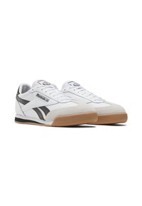 White athletic sneakers with black accents, suede toe cap, and a gum rubber sole. Features laces and Reebok branding on the tongue.