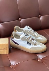 Sneakers bianchi in pelle con accenti in suede beige, tacco in stampa leopardata e suola in gomma testurizzata. Lacci con un motivo a righe. Scatola in legno inclusa.