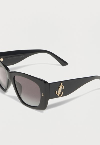 Μαύρα ορθογώνια γυαλιά ηλίου με φακούς με βαθμιαία σκουρότητα και χρυσό λογότυπο "JC" με περίπλοκη πλέξη στα πλαϊνά, παρουσιάζονται σε λευκό φόντο.