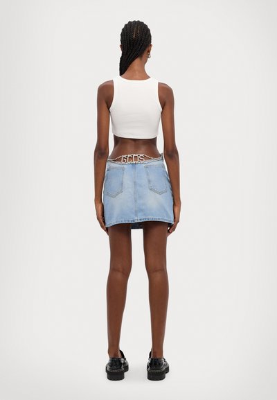 Svetlomodrá denimová sukňa s priliehavým strihom, s dvoma zadnými vreckami a ozdobným reťazovým opaskom. V kombinácii s bielym skráteným topom bez rukávov.