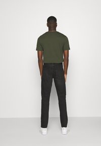 Calvin Klein Jeans CKJ 058 SLIM TAPER - Jeans Tapered Fit - denim black/black denim - Zalando.co.uk