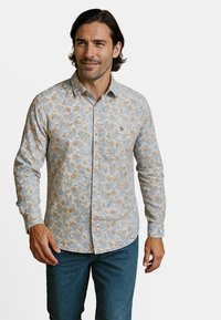 Lichtblauw overhemd met lange mouwen, voorzien van een bloemenpatroon in bruin en crèmekleur. Het shirt heeft een button-down kraag en een borstzakje.