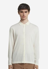 Långärmad skjorta med knappar i off-white, tillverkad av lättviktsmaterial, med en mjuk krage och rak nederdel samt manschetter vid ärmarna.