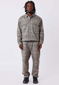 Conjunto de chaqueta y pantalones de patrón gris, hecho de un tejido texturizado, que presenta dos bolsillos en el pecho de la chaqueta y un corte relajado.