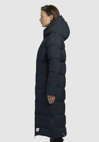 Cappotto imbottito lungo blu navy con cappuccio, design a righe verticali, tasche con zip e chiusura laterale con zip per una facile vestibilità.