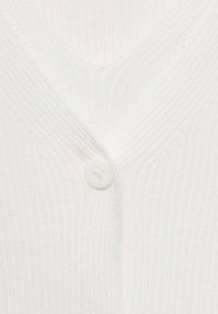 Gros plan sur un tissu en maille côtelée blanche avec un bouton blanc fermant un vêtement à col en V.
