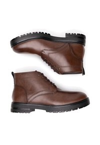 Hnědé kožené kotníkové boty s hladkým povrchem, šněrovacím designem a strukturovanou gumovou podrážkou. Boční šití dodává na formě.