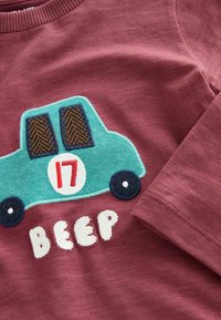 Burgundia pikki varrukatega särk, millel on sinise auto tikitud graafika, pruuni akna ja valgete tähtedega, mis kirjutavad "BEEP" all.