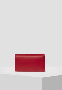 Clutch en cuir rouge avec une texture lisse, de forme rectangulaire et au design épuré. Pas de matériel ou de motifs visibles. Simple et minimaliste.