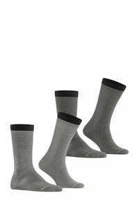 Quatre chaussettes fines rayées noir et blanc avec des poignets noirs, présentées dans un agencement décalé sur un fond blanc.