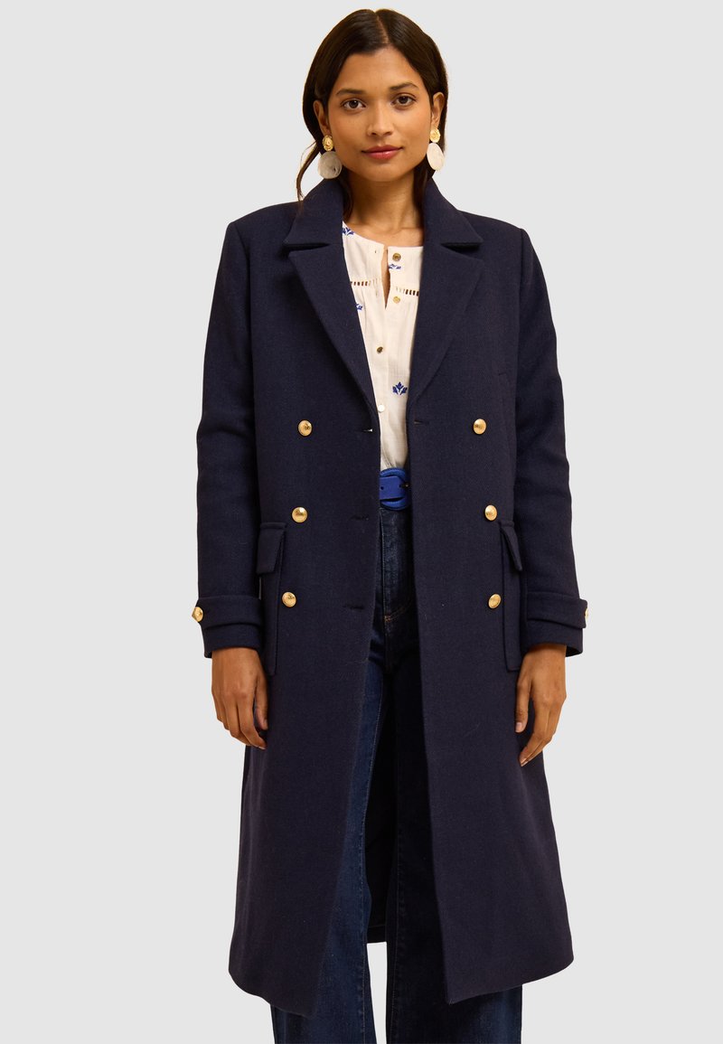 Cappotto doppiopetto in misto lana blu navy con bottoni dorati, revers a punte, tasche laterali e vestibilità dritta.
