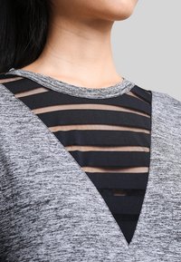 Top grigio con un design a maglia testurizzata, dotato di un pannello in rete nera sovrapposto a ritagli a strisce orizzontali in stile scollo a V.
