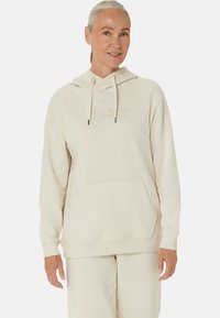 Beige hooded sweatshirt with a front pocket, featuring a tonal logo. Made of soft fabric, with ribbed cuffs and a smooth texture.