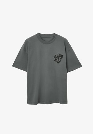 Camiseta de algodón gris con cuello redondo, mangas cortas y un gráfico negro en la parte izquierda del pecho. Presenta un corte relajado y una textura suave.