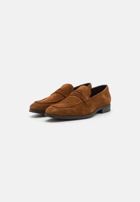 Loafers din suede maro cu vârf rotunjit și detalii minime de cusătură. Au o toc mic, păstrat și o căptușeală interioară netedă.
