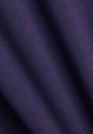 Nærbillede af mørkelilla strikstof, der viser detaljeret tekstur og subtile folder.