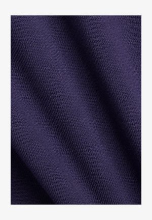 Nærbillede af mørkelilla strikstof, der viser detaljeret tekstur og subtile folder.