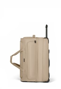 Valigia beige con ruote e soffice, dotata di manico estensibile nero, doppie cinghie per il trasporto e tasca frontale con cerniera, in posizione verticale su sfondo bianco.