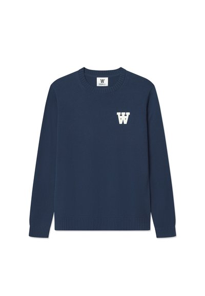 Tummansininen neulepusero, jossa on pyörökaulus, ribattu helma ja pitkät hihat. Vasemman rinnan kohdalla on valkoinen "W"-logo.