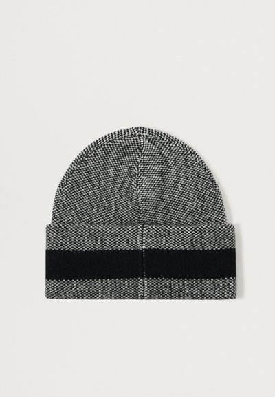 Pletená čepice v černobílém houndstooth vzoru, má jednobarevný černý lem, kulatou špičku a texturovanou tkaninu.