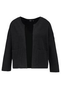 Cardigan noir à ouverture frontale, fabriqué en tissu doux. Il présente une coupe décontractée, des manches larges et deux poches avant. Texture lisse, design minimal.