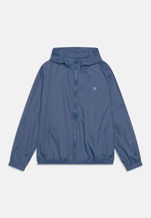 Veste coupe-vent légère bleue à capuche avec fermeture éclair frontale, poignets élastiques, poches latérales et petit logo blanc sur la poitrine.