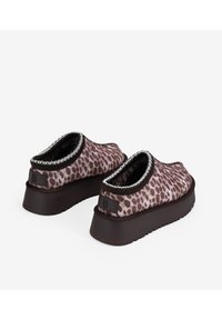 Zapatos con estampado de leopardo en marrón y beige, con perfil bajo, acabado texturizado y suela gruesa marrón. Cuentan con un interior acolchado y ribete en contraste.