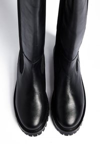 Črne usnjene gležnarje s elegantnim dizajnom, gladko teksturo in elastičnimi stranskimi paneli, opremljene z robustnimi gumijastimi podplati za boljši oprijem.