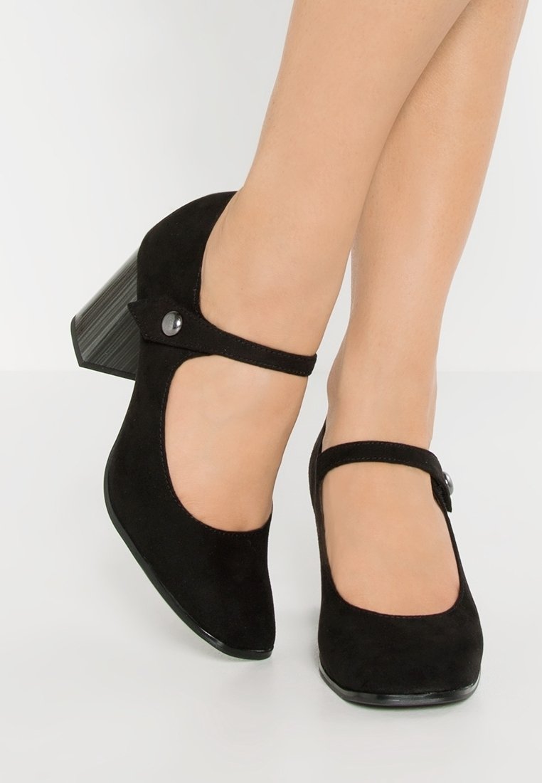 Czarne zamszowe szpilki Mary Jane z okrągłym noskiem, regulowanym paskiem oraz średnim słupkowym obcasem z okrągłym akcentem.