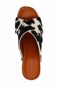 Zwart-witte koeienhuid slidesandal met een kruisende bandontwerp, bruine gestructureerde binnenzool en minimalistische vorm.