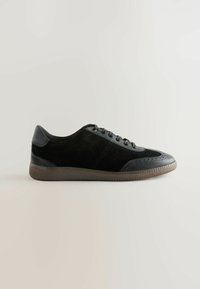 Svarta sneakers med ovandel i mocka, läderdetaljer, rund form och strukturerad gummisul. Har snörning och perforerade detaljer.