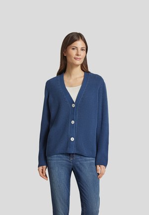 Blue knitted cardigan with a V-neck, five buttons, ribbed texture, and long sleeves, paired with a light shirt and jeans.