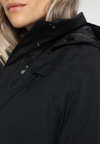 Black weather-resistant jacket with a high collar, front zipper, and adjustable hood. Features logo and textile texture details.
