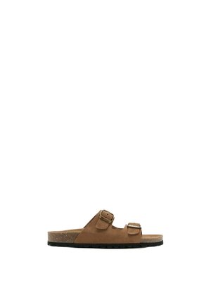 Sandalia tipo slide de ante marrón con dos correas ajustables con hebillas y una plantilla de corcho sobre una suela negra, vista lateral.