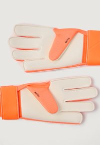 Brankárske rukavice s bielymi dlani a jasne oranžovými akcentmi, ktoré majú štruktúrované úchopové plochy a suché zips na zápästí pre bezpečné uchopenie.