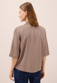 Kortärmad blus i mauve med ett mjukt, lätt tyg. Har en avslappnad passform och subtil krage. Tillsammans med mörkblå jeans.