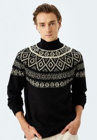 Zwarte wollen trui met een hoge hals, voorzien van een Fair Isle-patroon in roomkleur, geometrische ontwerpen over de borst en schouders.