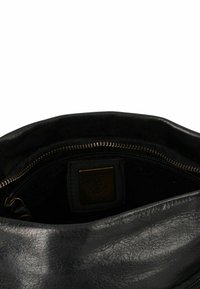Borsa a tracolla in pelle nera con una texture liscia. Caratterizzata da una chiusura con zip e una fodera in tessuto. Etichetta interna visibile. Design semplice.