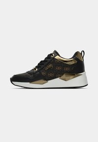Sneaker nera con accenti dorati, con tomaia in tessuto pattern, sovrapposizioni in pelle, suola bianca spessa e dettagli angolari sui lati.