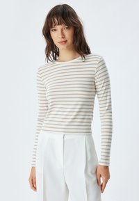 Langsleeve top met horizontale beige en witte strepen, ronde halslijn en slim fit. Gedragen met witte op maat gemaakte broek.