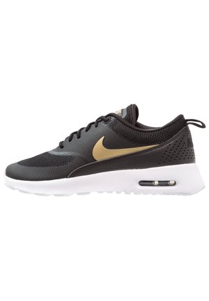 Schwarzer Sportschuh mit goldenem Nike-Swoosh, weißer Sohle, sichtbarer Luftpolsterung, Schnürung vorne und Mesh-Obermaterial.