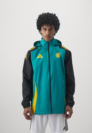 Una chaqueta cortavientos en color teal y negro con detalles en amarillo, que cuenta con un cierre frontal, capucha ajustable y puños elásticos. Logotipo de Adidas exhibido.