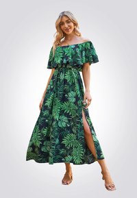 Vestido maxi de hombros al aire en tela negra con estampado de hojas verdes, que presenta una cintura ceñida y una abertura lateral alta hasta el muslo.