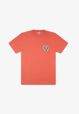 Camiseta naranja de manga corta con un pequeño logo de Wrangler y emblema de águila en el lado izquierdo del pecho, cuello redondo, talla mediana.