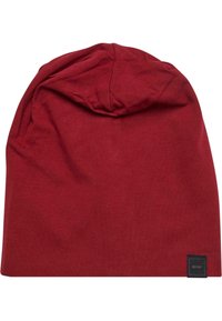 Cappello di cotone rosso con una texture morbida, caratterizzato da una parte superiore arrotondata e una piccola etichetta nera sul lato. Design leggero e flessibile.